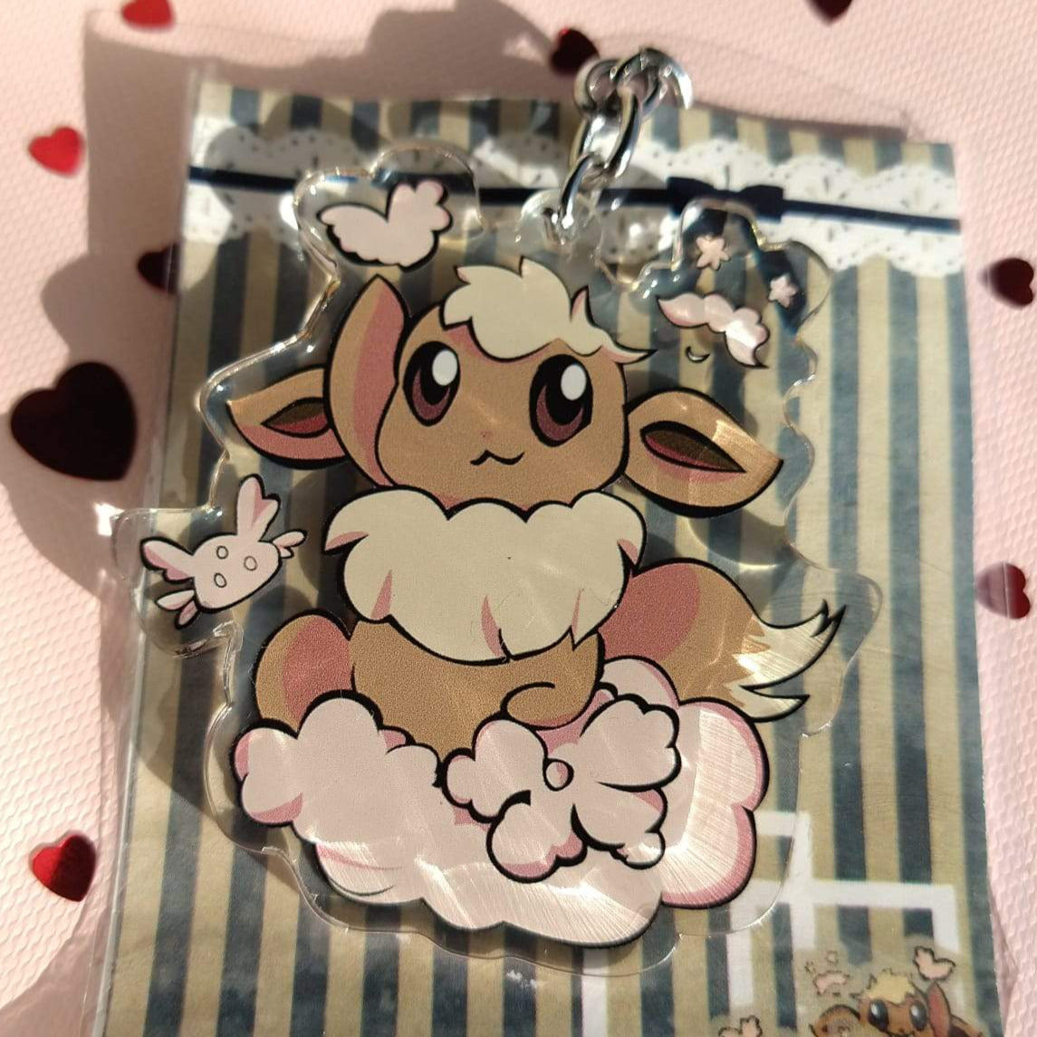 Acrylic Eevee keychain sitting on a pink cloud, on its striped backing card