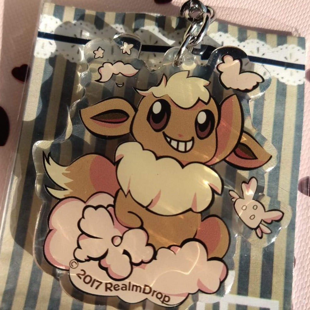 Grinning Eevee on a pink cloud acrylic keychain with a small flying cloud creature