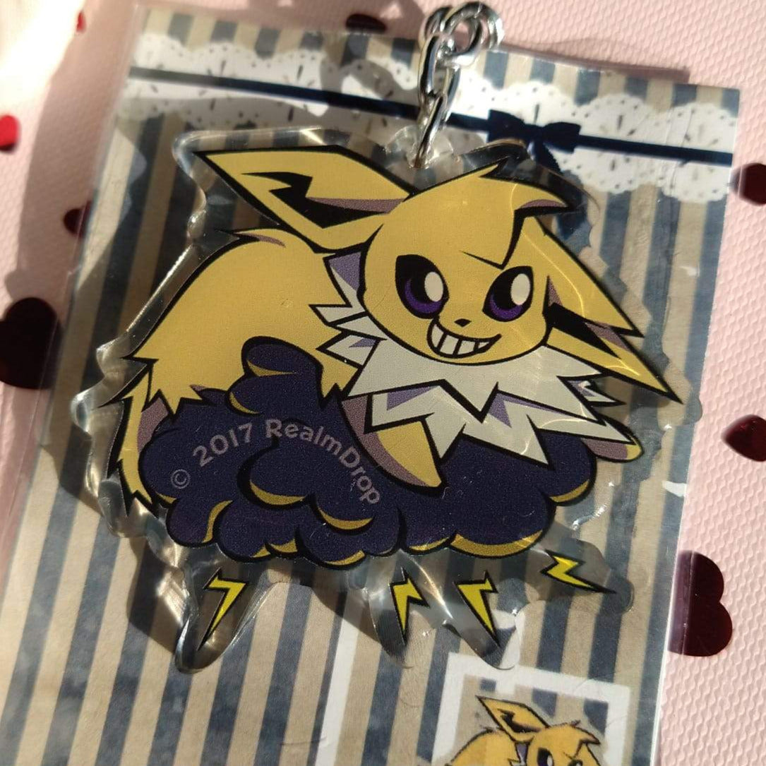 Grinning Jolteon on a dark storm cloud acrylic keychain, on its striped backing card