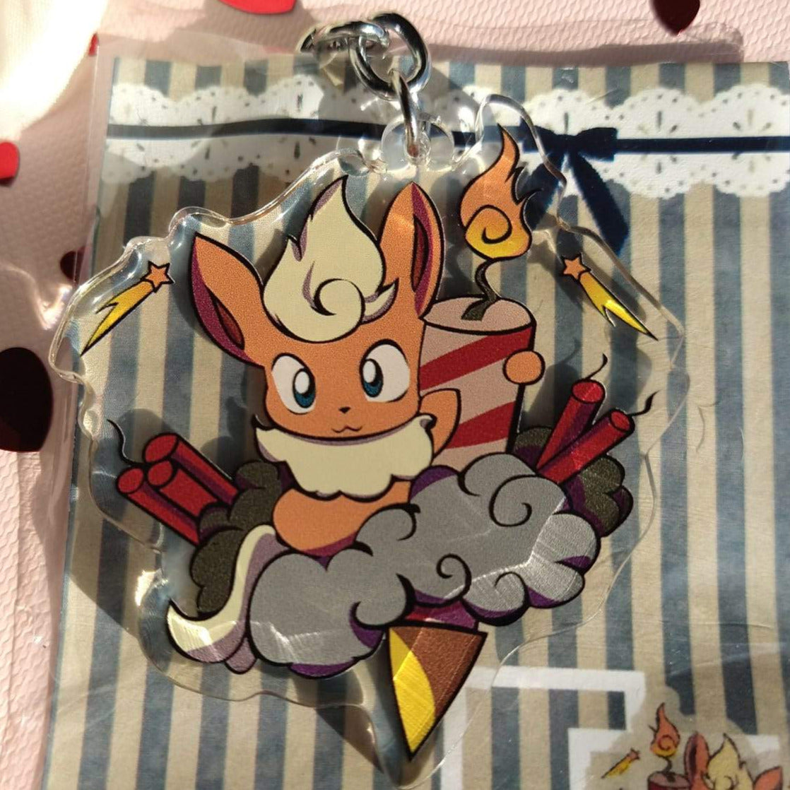 Acrylic Flareon keychain holding a lit firework on a smoke cloud with firecrackers