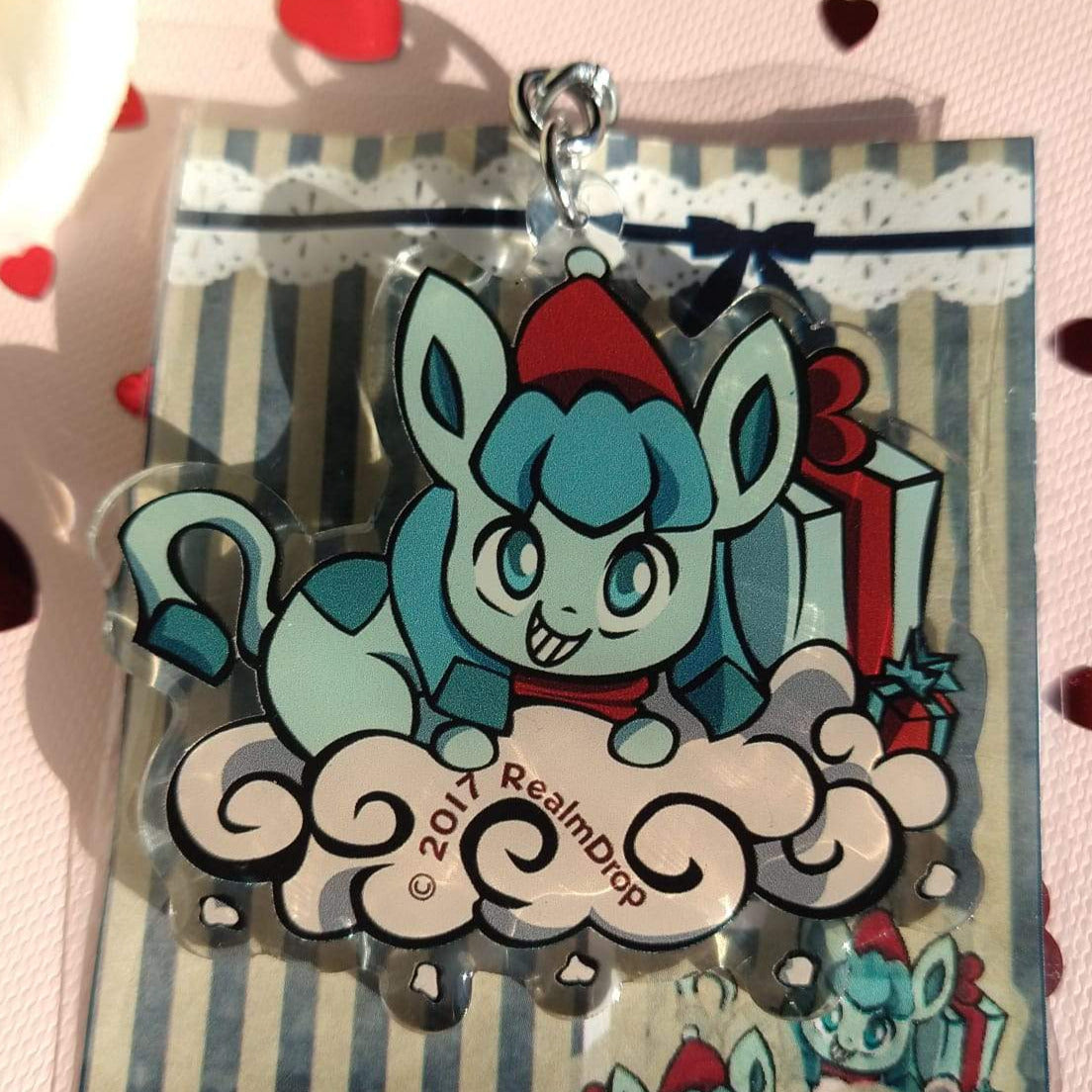 Grinning Glaceon in a Santa hat and scarf on a snowy cloud acrylic keychain