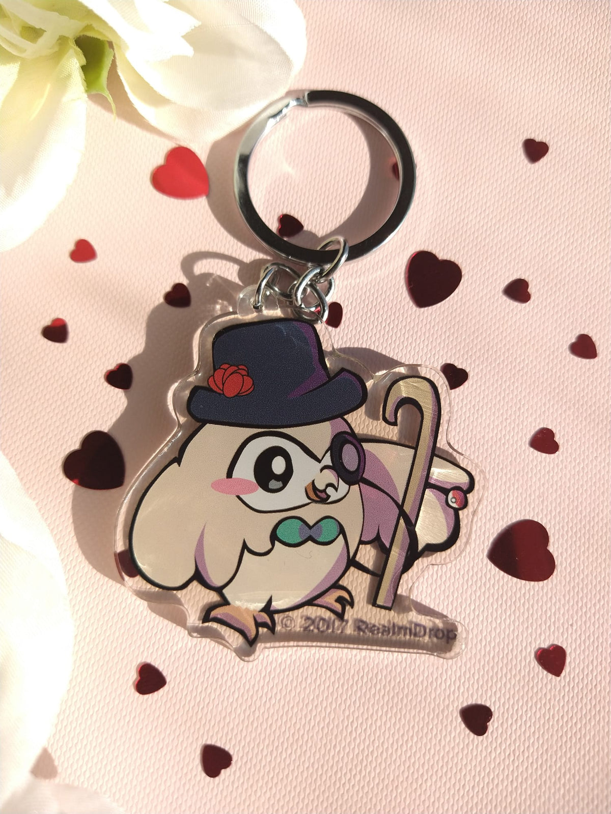 Acrylic Rowlet keychain in a top hat, monocle and cane on pink with red hearts