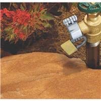 Hose bibb lock with padlock fitted on an outdoor faucet in a garden bed