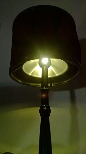 Retro desk lamp lit up in a dark room, glowing under its black shade