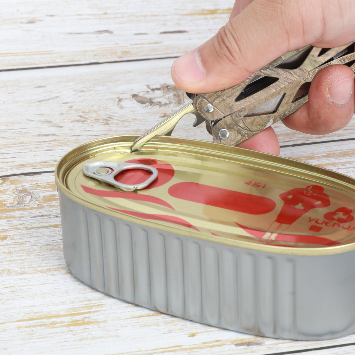 Camo multi-tool's can opener prying the lid of a tin can