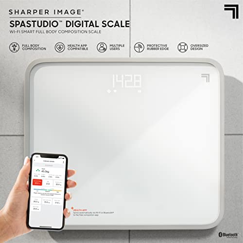 White glass smart scale on tile with a hand holding a phone showing body stats