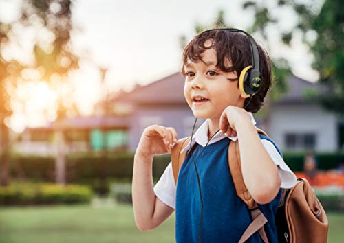 Boy with a backpack wearing black and yellow Batman headphones outdoors