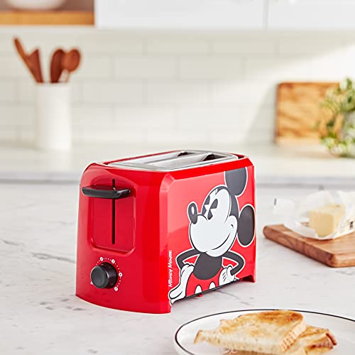 Red Mickey Mouse toaster on a kitchen counter beside a plate of toast
