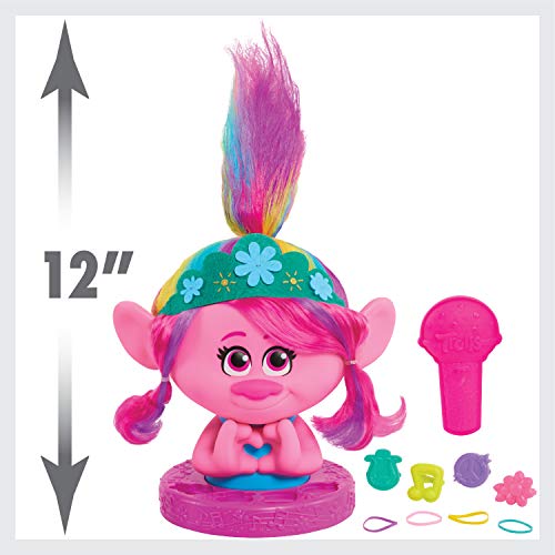 Pink troll styling head beside a 12 inch height arrow, with brush and clips