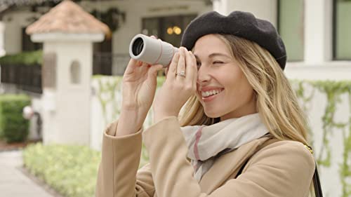 Smiling woman in a beret looking through the handheld scope outdoors