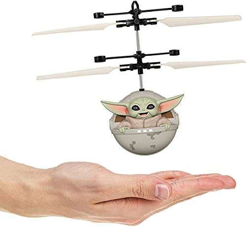 Flying toy of the green alien child in his pod hovering above a hand