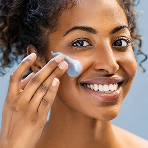 Smiling woman smoothing light blue gel cream mask onto her cheek