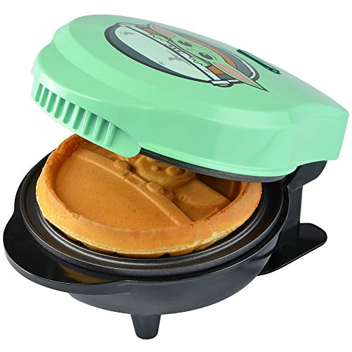 Lid lifted on the green waffle maker revealing a cooked Grogu waffle