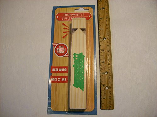 Wooden train whistle with a green locomotive print on its card beside a ruler