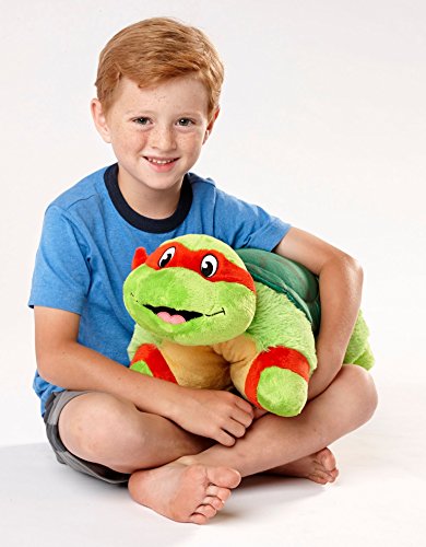 Smiling boy sitting cross-legged hugging the Raphael turtle pillow