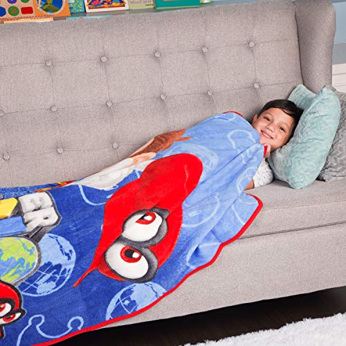 Smiling child lying on a sofa under the blue Mario Odyssey throw