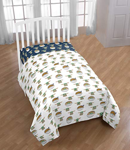 Bed with white sheets printed with Grogu and his pod, navy fitted sheet below