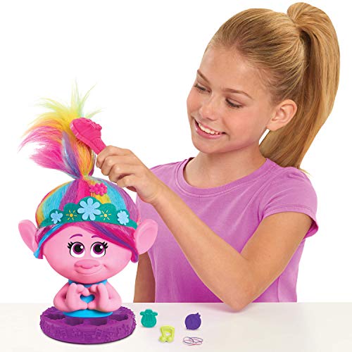 Girl brushing the rainbow hair of a pink troll styling head