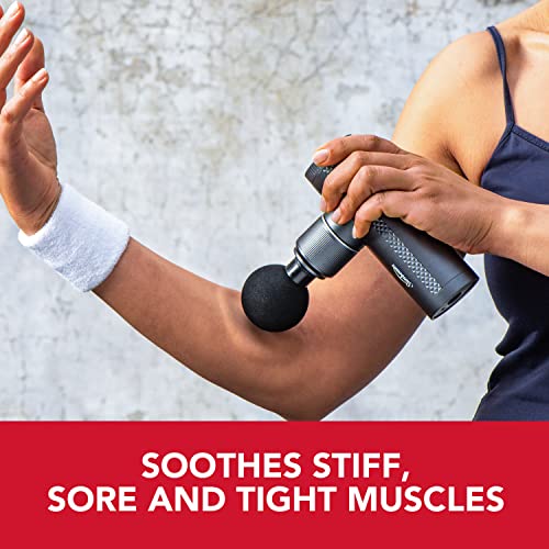 Woman using the massage gun on her upper arm: soothes stiff, sore muscles