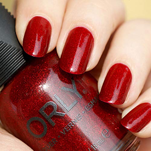 Red sparkle polish on nails, held against the bottle