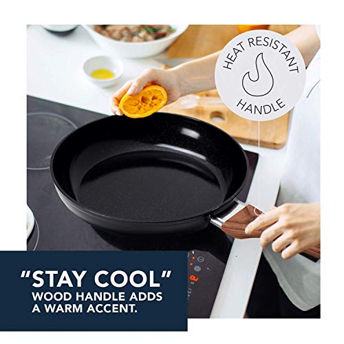 Hand squeezing an orange over the black pan on a cooktop: stay cool handle