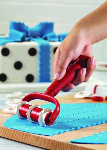 Hand rolling the red ribbon cutter over blue fondant beside a polka dot gift cake