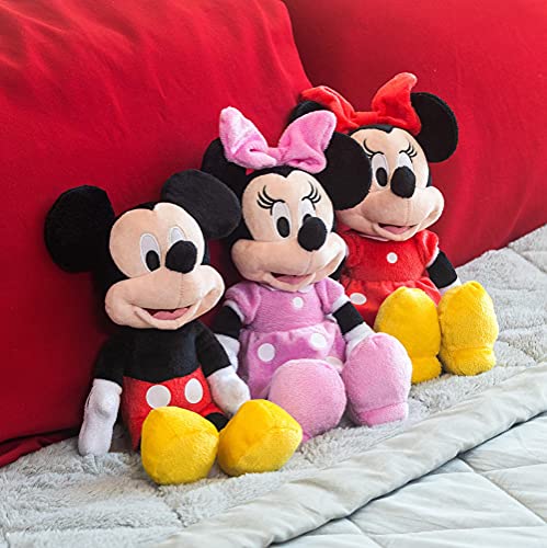 Three mouse plushes in red shorts, pink dress and red dress on a bed