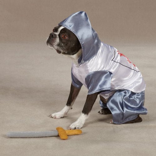 Boston terrier sitting in the hooded knight costume beside a plush sword