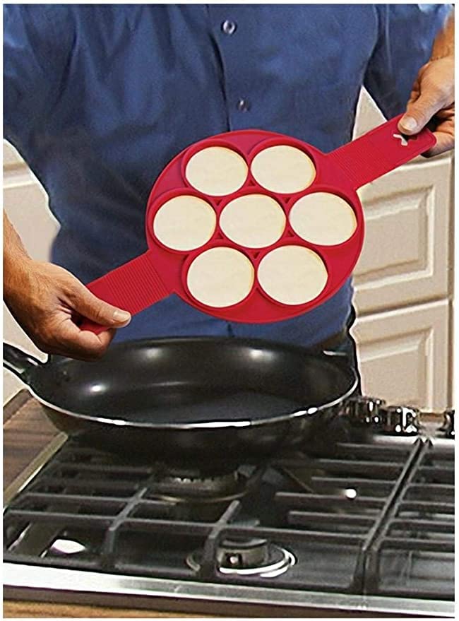 Man lifting a red silicone mould of seven round pancakes off a frying pan