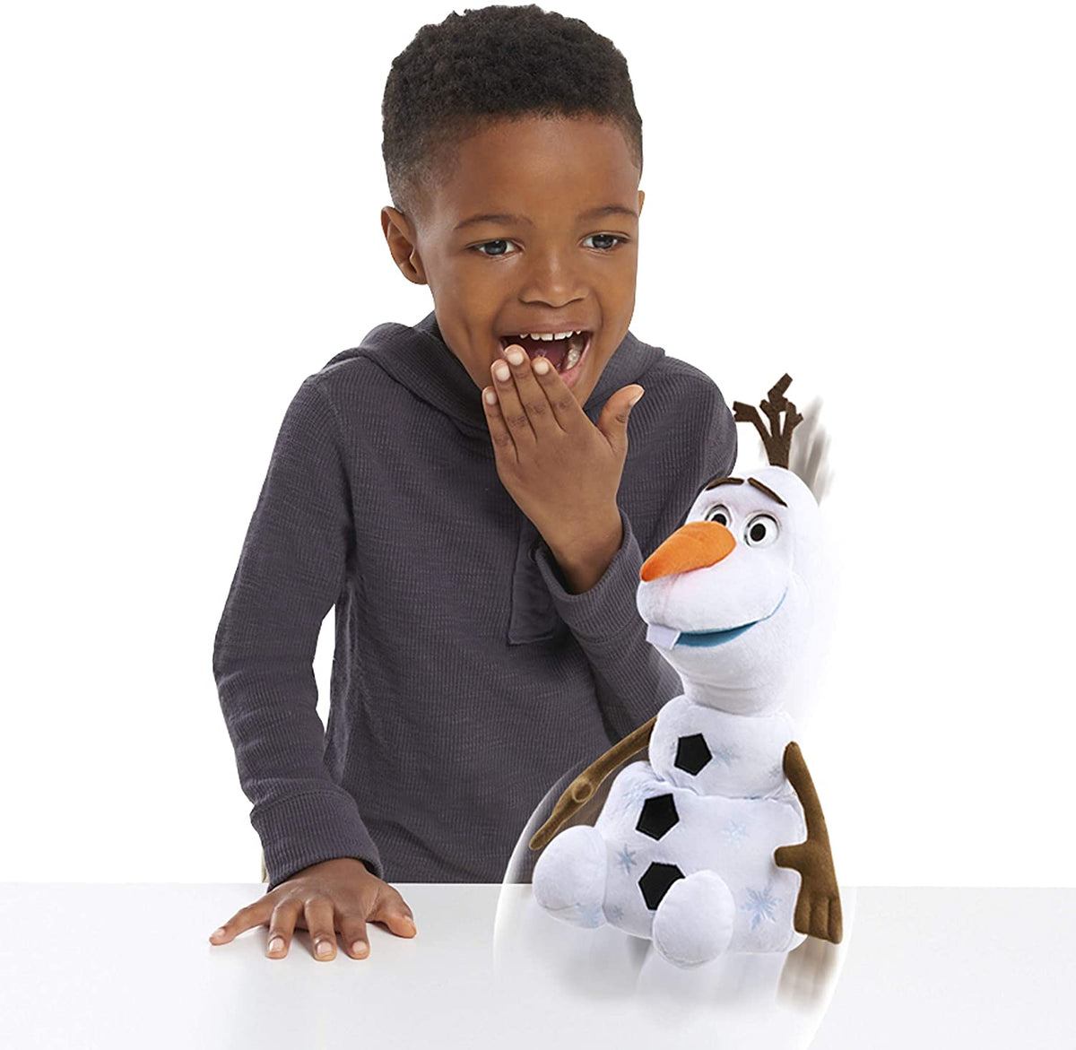 Child laughing as the Olaf toy springs its head up on a table