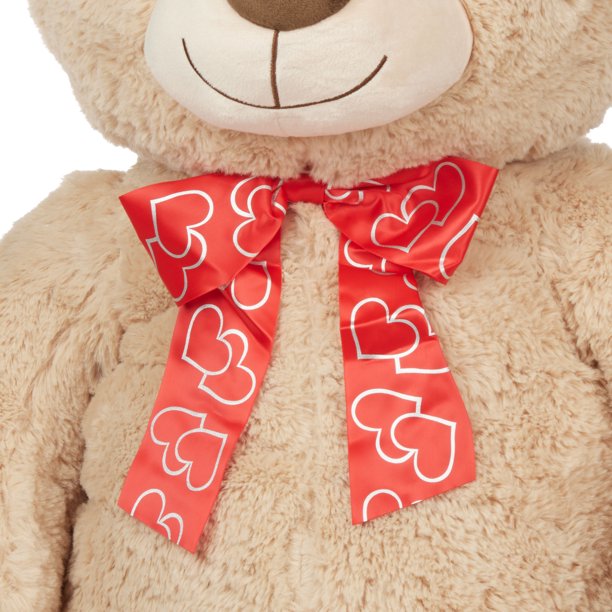 Close-up of the red ribbon bow with white heart outlines on the tan bear