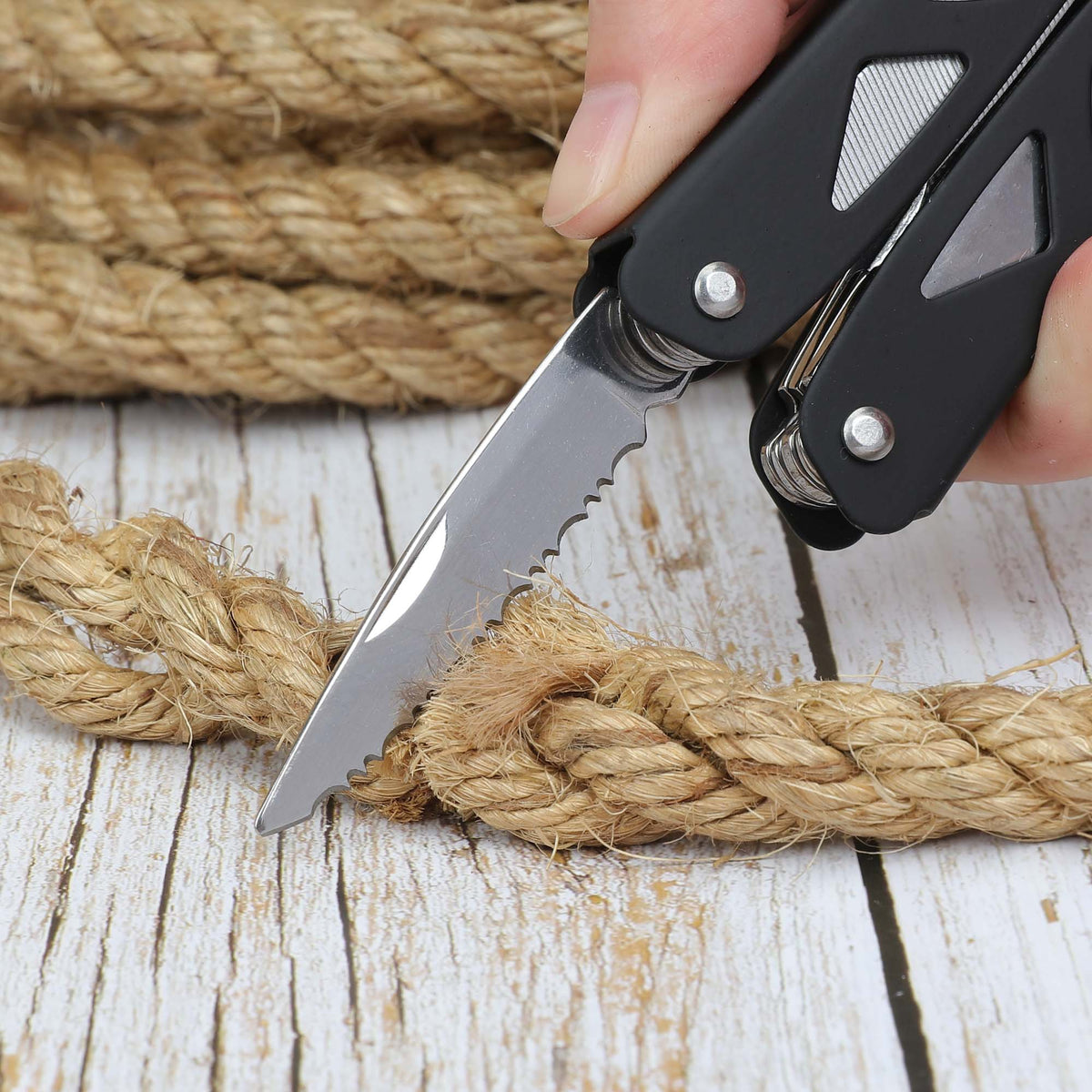 Black multi-tool serrated blade cutting through jute rope