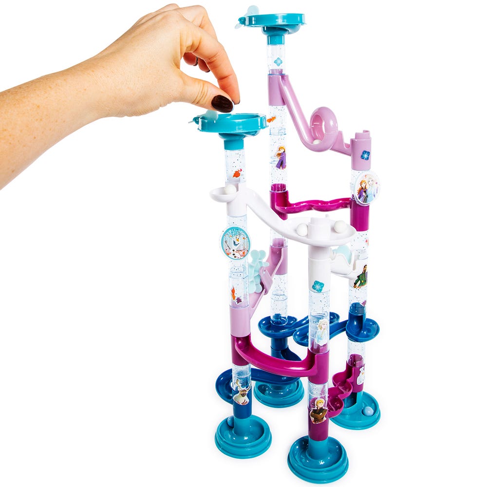 Hand dropping a marble into the built Frozen II teal and purple marble run