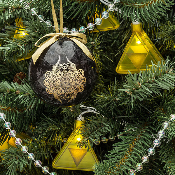 Yellow Triforce string lights glowing on a Christmas tree beside a black Zelda bauble