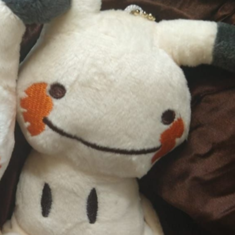 Close-up of a Mimikyu keychain plush with orange cheeks and a wide smile