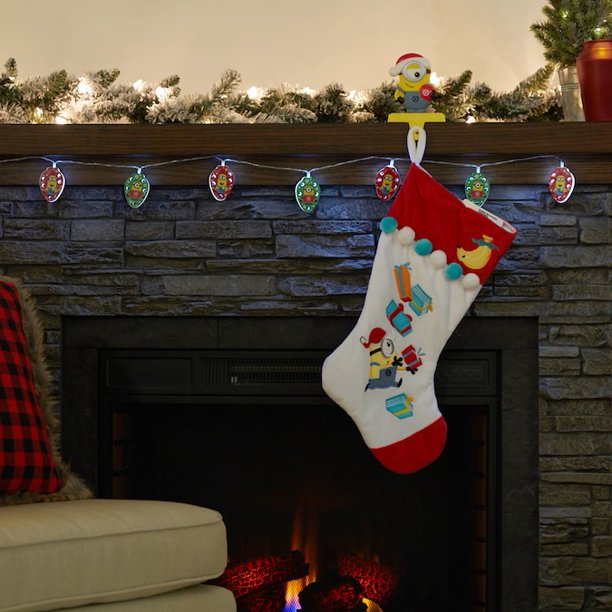 Minions string lights glowing on a fireplace mantel beside a Minion stocking