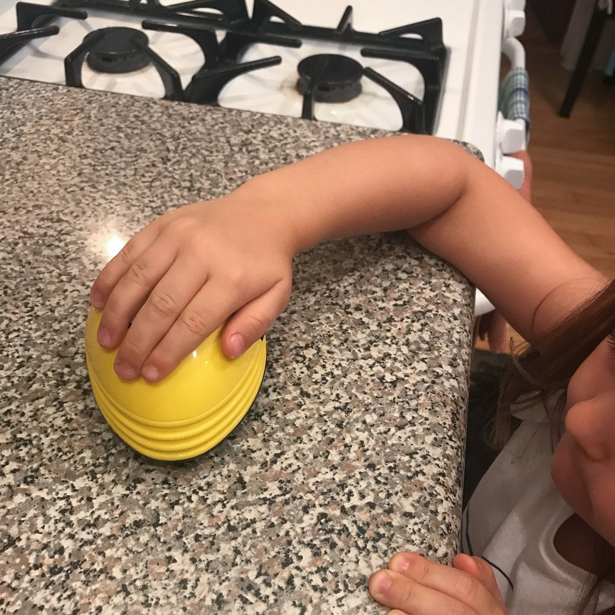 Child's hand pushing the yellow mini vacuum across a granite counter